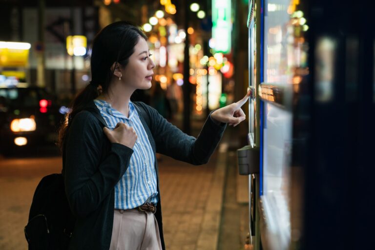 woman pushing vending machine button to buy drink